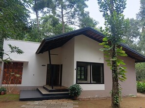 Ein modernes, zweistöckiges Haus mit flachem Dach, großen Fenstern und einer kleinen Veranda.