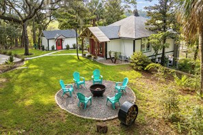 Ein Garten mit Feuerstelle, Sitzgelegenheiten im Freien und einem gepflegten Rasen.
