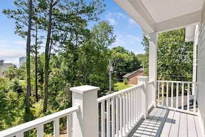 A porch with a white railing overlooking a residential area with trees and a clear sky. - Electric Octopus-2.5 Blocks-Beach-Pets (Myrtle Beach)