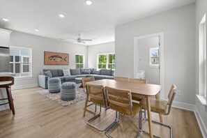 Ein modernes Wohnzimmer mit einem grauen Sofa, einem Holzespeisetisch mit Stühlen und einem Deckenventilator.