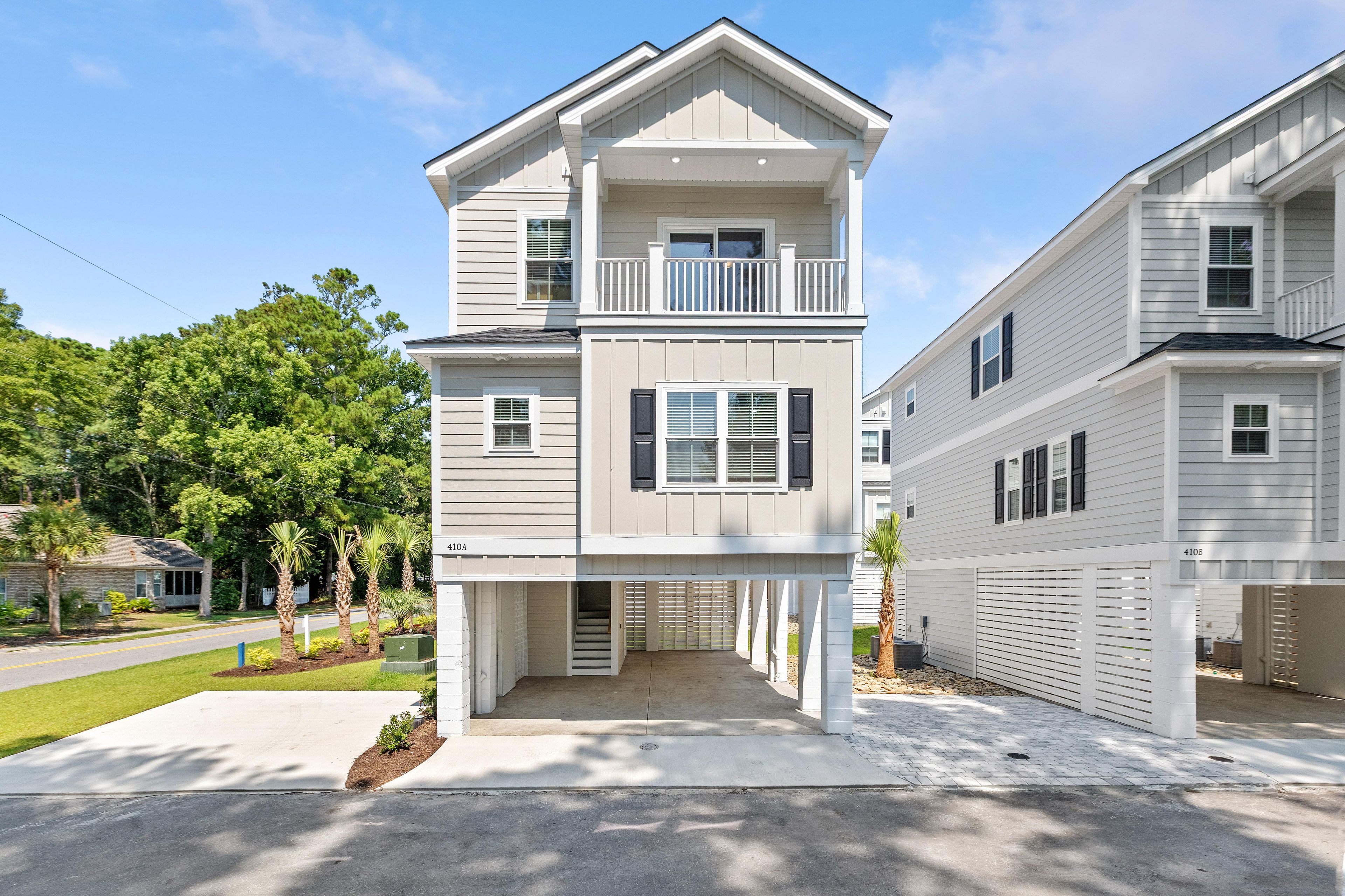 A two-story residential building with a balcony on the upper floor, a garage on the right, and a well-maintained lawn.