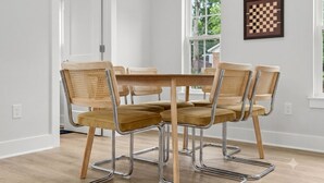 Comedor con una mesa de madera y seis sillas de respaldo trenzado y asientos acolchados.