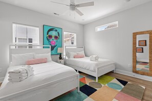 Ein Schlafzimmer mit zwei Betten, einem Deckenventilator, einem farbenfrohen Teppich und einem großen Spiegel.