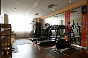 A gym with treadmills, weight machines, and a mirror wall.