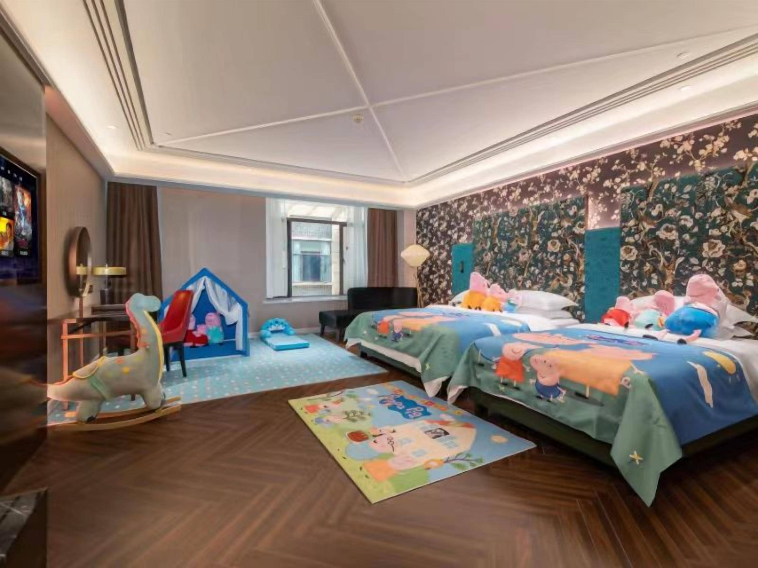 Habitación de hotel con dos camas, una zona de juegos y un ventanal grande.