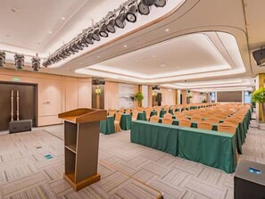 Un salón de conferencias con una larga mesa, un atril y un diseño de techo moderno.