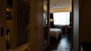 A hotel room with a bed, a desk, a chair, a lamp, and a view of the city through the window. - Paco Hotel Chimelong Nancun Wanbo Metro (Guangzhou)