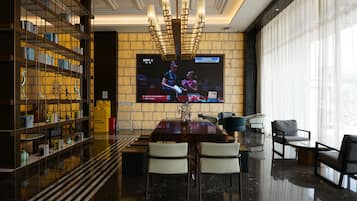 Un intérieur moderne avec un grand téléviseur à écran plat, un coin repas et une bibliothèque.