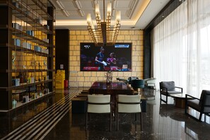 Um interior moderno com uma televisão de tela plana grande, uma área de jantar e uma estante de livros.