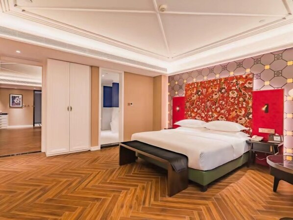 Une chambre d’hôtel avec un lit, une banquette, une armoire et un mur d’accent de couleur rouge.