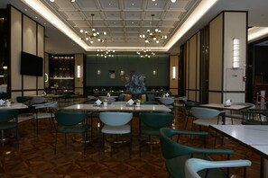 Un restaurant avec un plafond haut, de nombreuses tables et chaises, et une pièce maîtresse décorative.