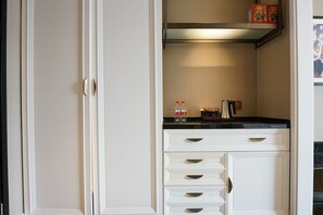 A kitchen with white cabinetry, a black countertop, and a stainless steel range hood.