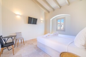A hotel room with a bed, a desk, a chair, a television, and a window.