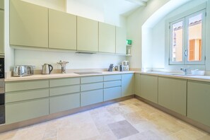Cozinha moderna com armários verde-claros, forno embutido e janela com vista para o exterior.