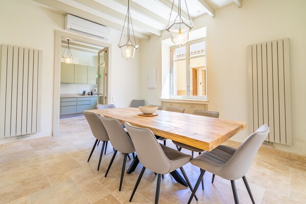 A spacious dining area with a large wooden table, six chairs, and pendant lighting.