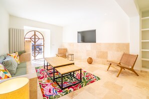A living room with a sofa, chairs, a TV, and a colorful rug.