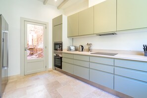 A modern kitchen with light-colored cabinets, a built-in oven, a toaster, and a coffee maker.