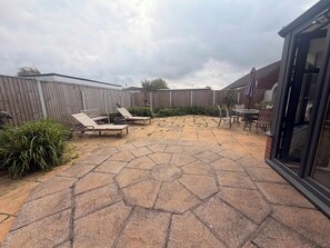 A backyard with hexagonal stone flooring, a wooden fence, and outdoor furniture. - Moorehouse Holiday Let 3-Bed Bungalow (Lancashire)
