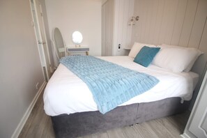 Ein Schlafzimmer mit einem Bett, einem Nachttisch, einem Spiegel und einer Wandleuchte.