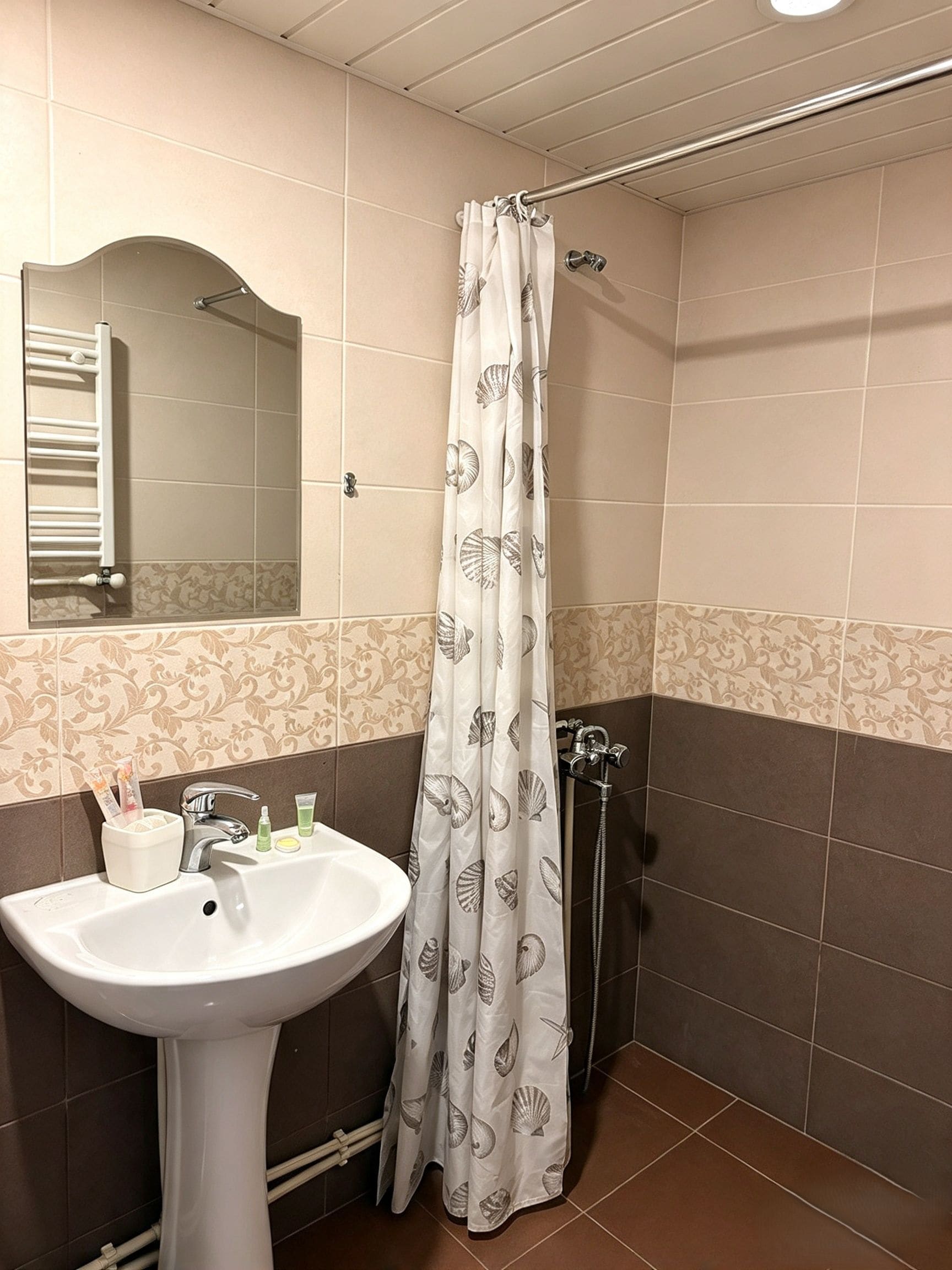 A bathroom with a white sink, a mirror, a shower with a white curtain, and a towel rack.