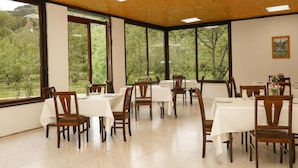Un comedor con mesas y sillas, ventanas amplias y vista a zonas verdes exteriores.