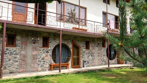 A stone building with a balcony, multiple windows, and a pine tree in the foreground. - Restland Hotel  (Dilijan)