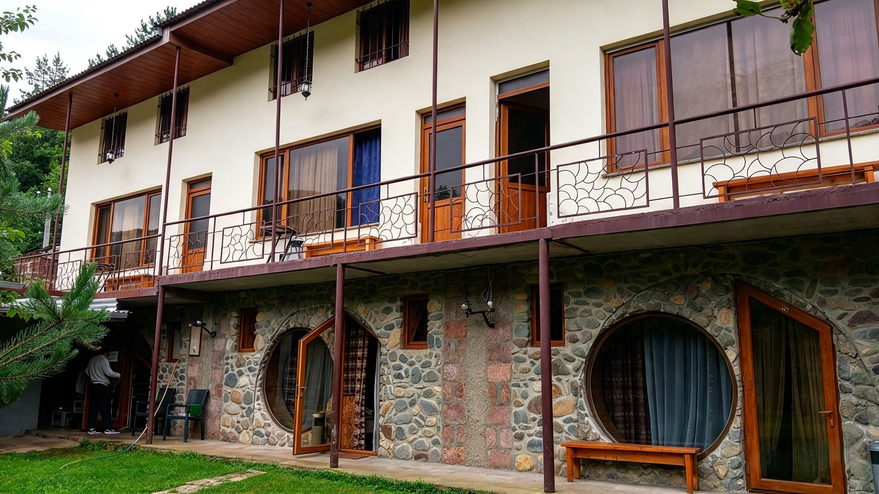 Un edificio de dos plantas con fachada de piedra, varias ventanas y un balcón con barandilla metálica.