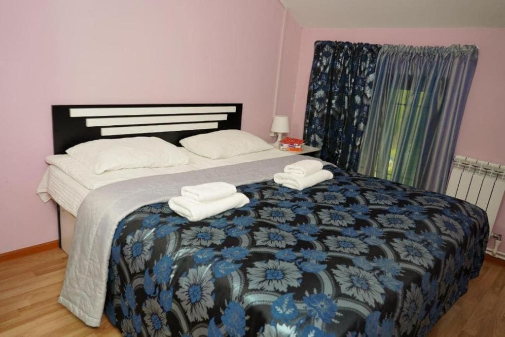 Una cama individual con cabecera, una mesita de noche con lámpara y una ventana con cortinas.