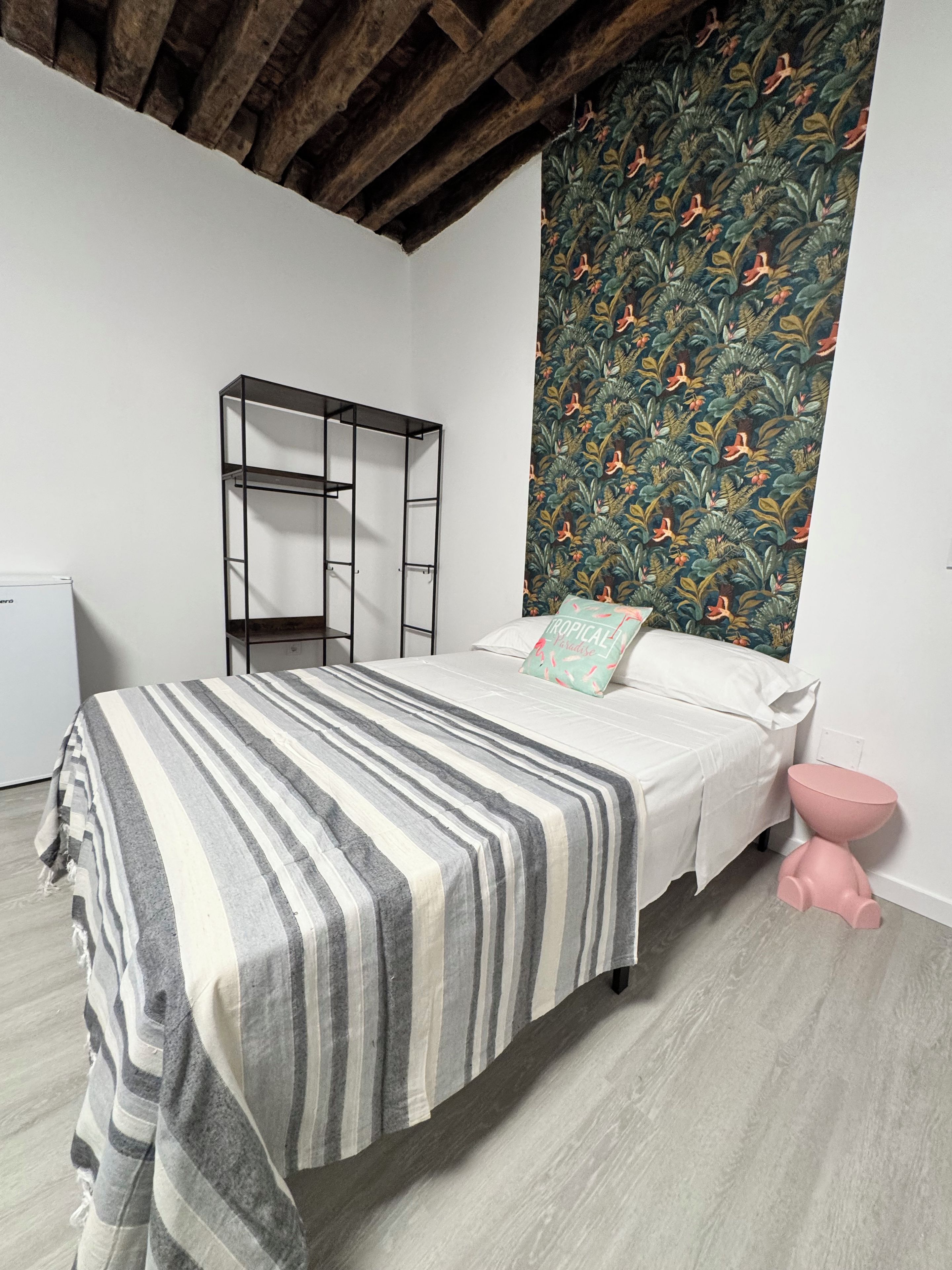 A bedroom with a bed, a wardrobe, a toilet, and a patterned wall.