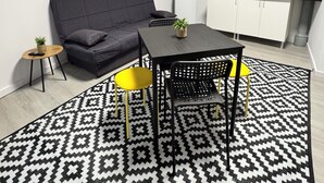 A modern living space with a sofa, a dining table with chairs, a kitchen area, and a patterned rug. - APARTAMENTOS MELISA 12 (Madrid)
