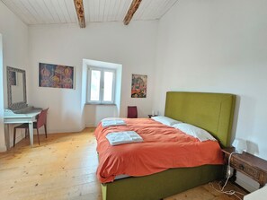 Ein Schlafzimmer mit einem Bett, einem Schreibtisch, einem Sessel und zwei Bildern an der Wand.