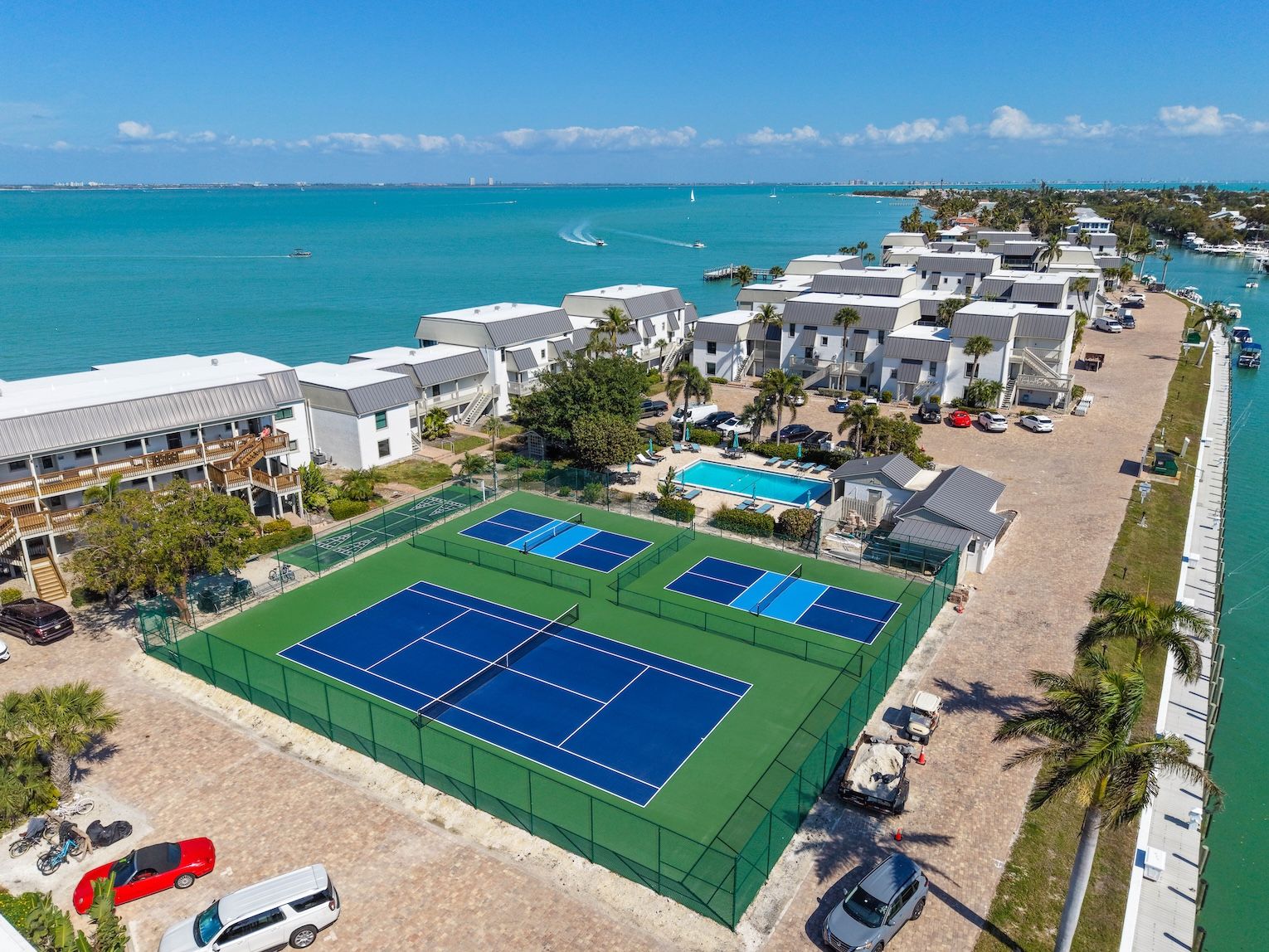 Un hotel frente al mar con canchas de tenis, piscina y vistas a la playa.