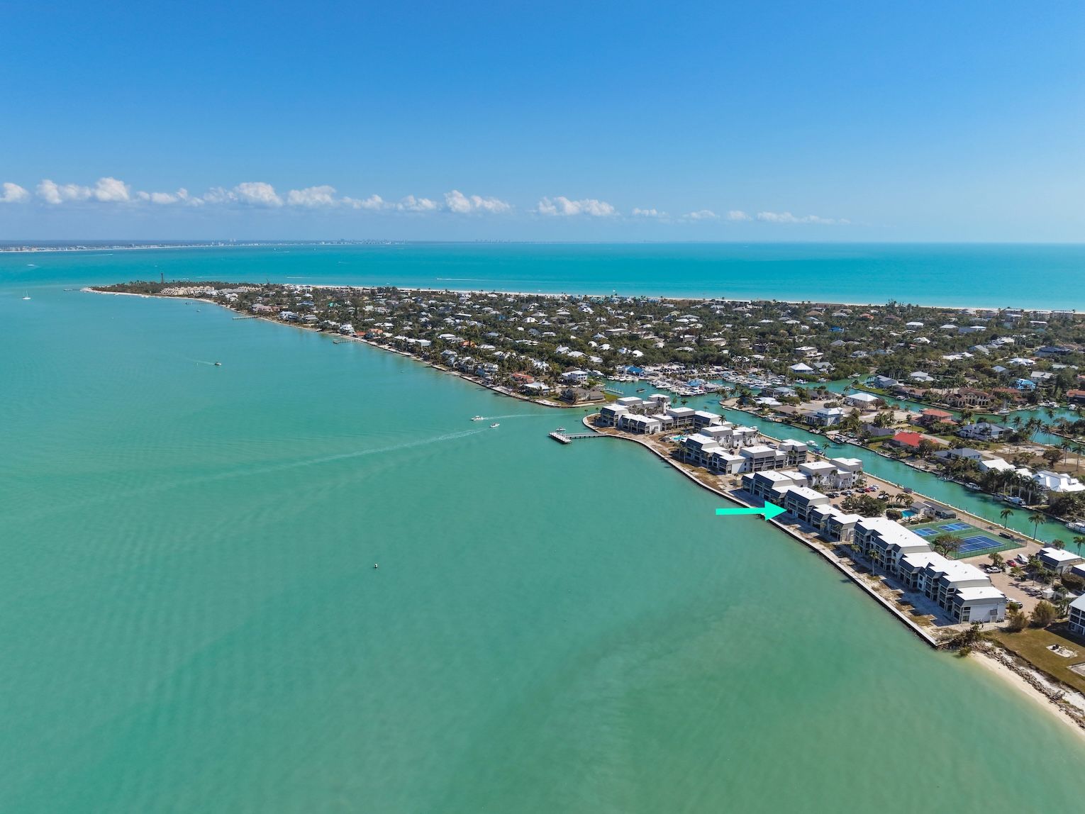 An aerial view of a coastal residential area with a marina and a long stretch of beachfront properties.