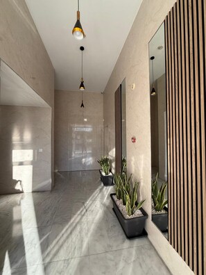 A modern hallway with marble flooring, potted plants, and pendant lighting. - Alijar Lux Bormujos (Bormujos)