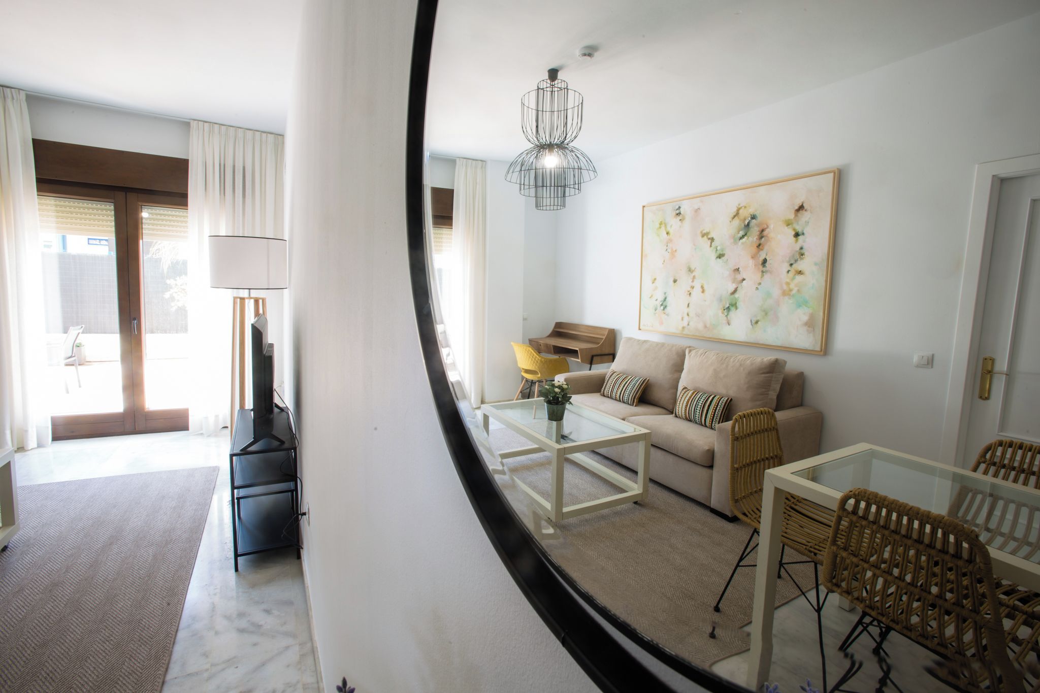A modern living room with a sofa, coffee table, and chairs, a dining area with a table and chairs, and a large abstract painting on the wall.