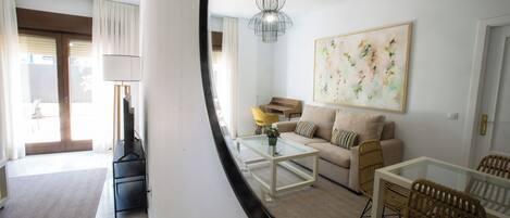 A modern living room with a sofa, coffee table, and chairs, a dining area with a table and chairs, and a large abstract painting on the wall.