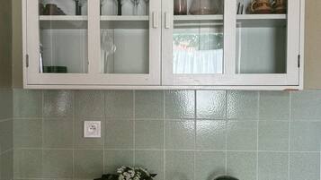 Eine Küche mit weißen Schränken, einem Spülbecken und einer grün gefliesten Rückwand.