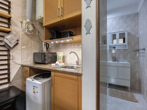 A modern kitchen with a built-in microwave, coffee maker, and a dishwasher. - Beachside Nomad - Studio near Armação Beach (Armação de Pêra)