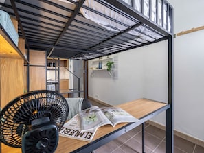 A bunk bed with a wooden table and a magazine, a black fan, and a small shelf with a plant. - Beachside Nomad - Studio near Armação Beach (Armação de Pêra)
