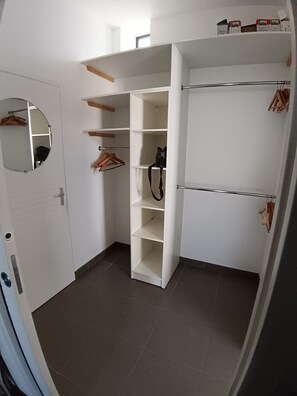 A walk-in closet with open shelves, a hanging rod, and a mirrored closet door. - La Maison de Jeanne - Maison familiale atypique à Brem sur mer (Brem-sur-Mer)