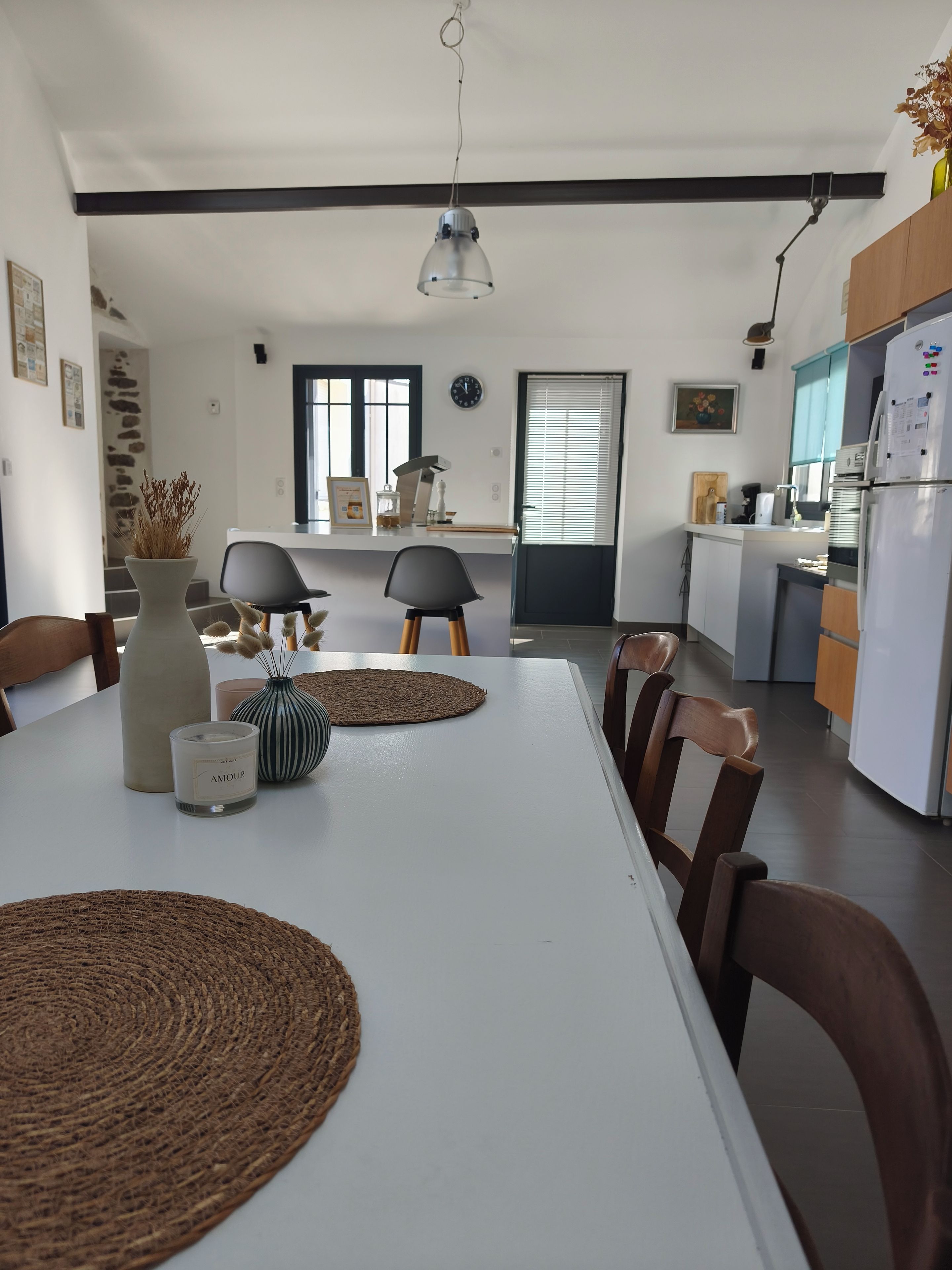 A modern kitchen with a dining table, chairs, and a hanging light fixture.