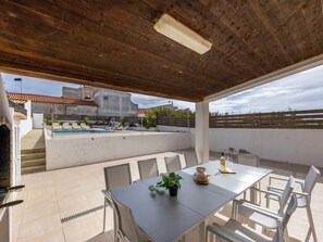 An outdoor patio with a pool, a dining table with chairs, and a view of a building in the background. - The Sagres House - Village Pool Retreat (Sagres)