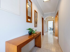 Un couloir avec un banc en bois, une plante en pot et des miroirs accrochés aux murs.