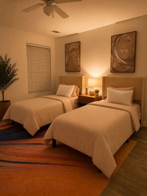 A hotel room with two beds, a ceiling fan, artwork on the walls, and a potted plant. - Cozy 3BR Home - Game Days & Family Stays (Tuscaloosa)