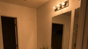 Un bagno con due lavandini, un WC, uno specchio e una piccola pianta.
