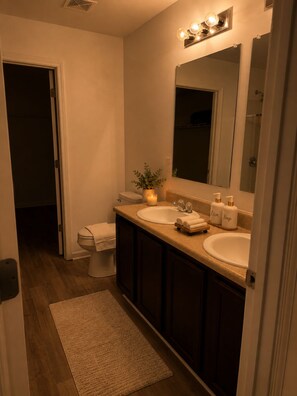 A bathroom with two sinks, a toilet, a mirror, and a small plant. - Cozy 3BR Home - Game Days & Family Stays (Tuscaloosa)
