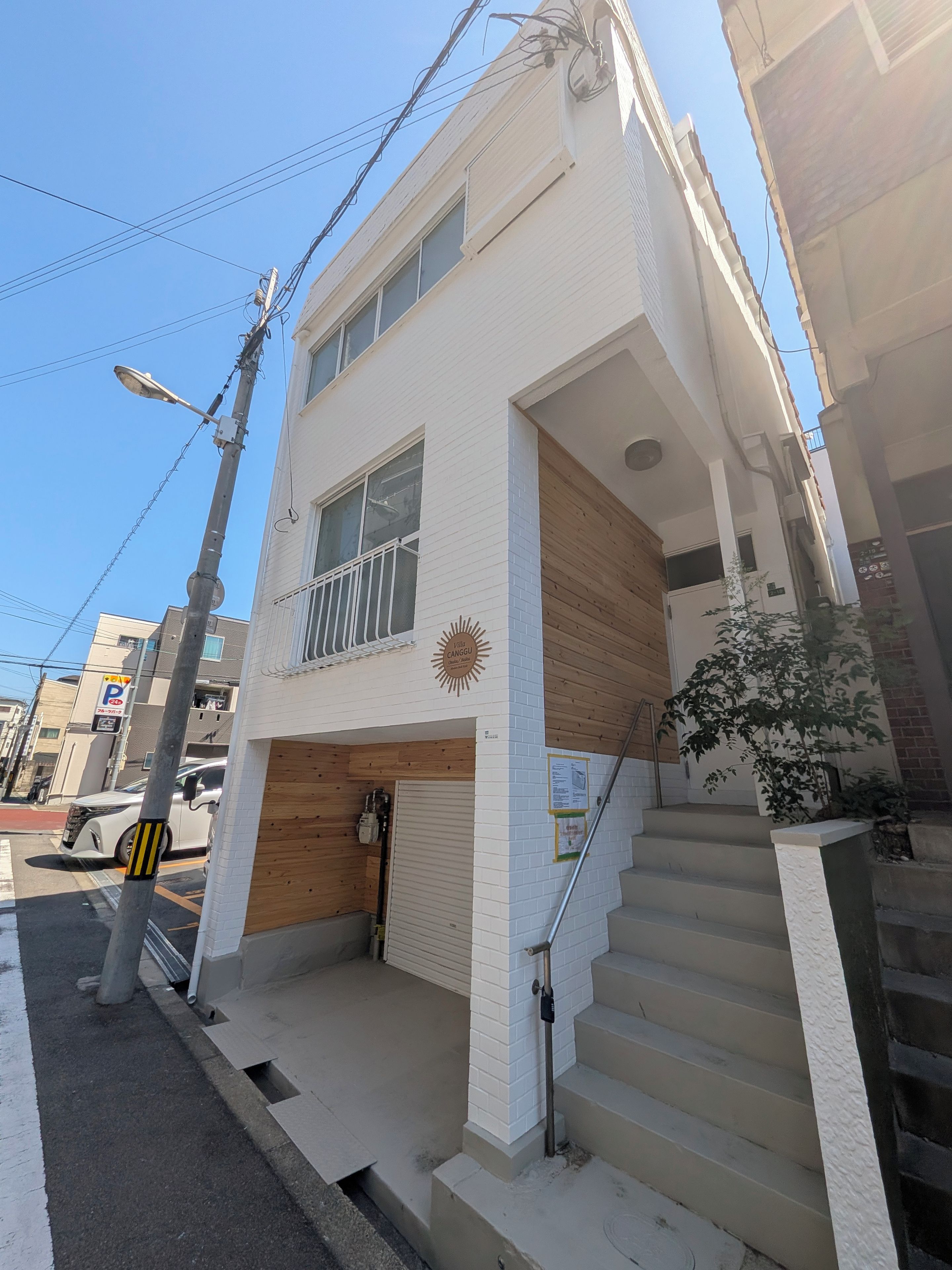 A two-story building with a garage, wooden paneling, and a sun emblem.