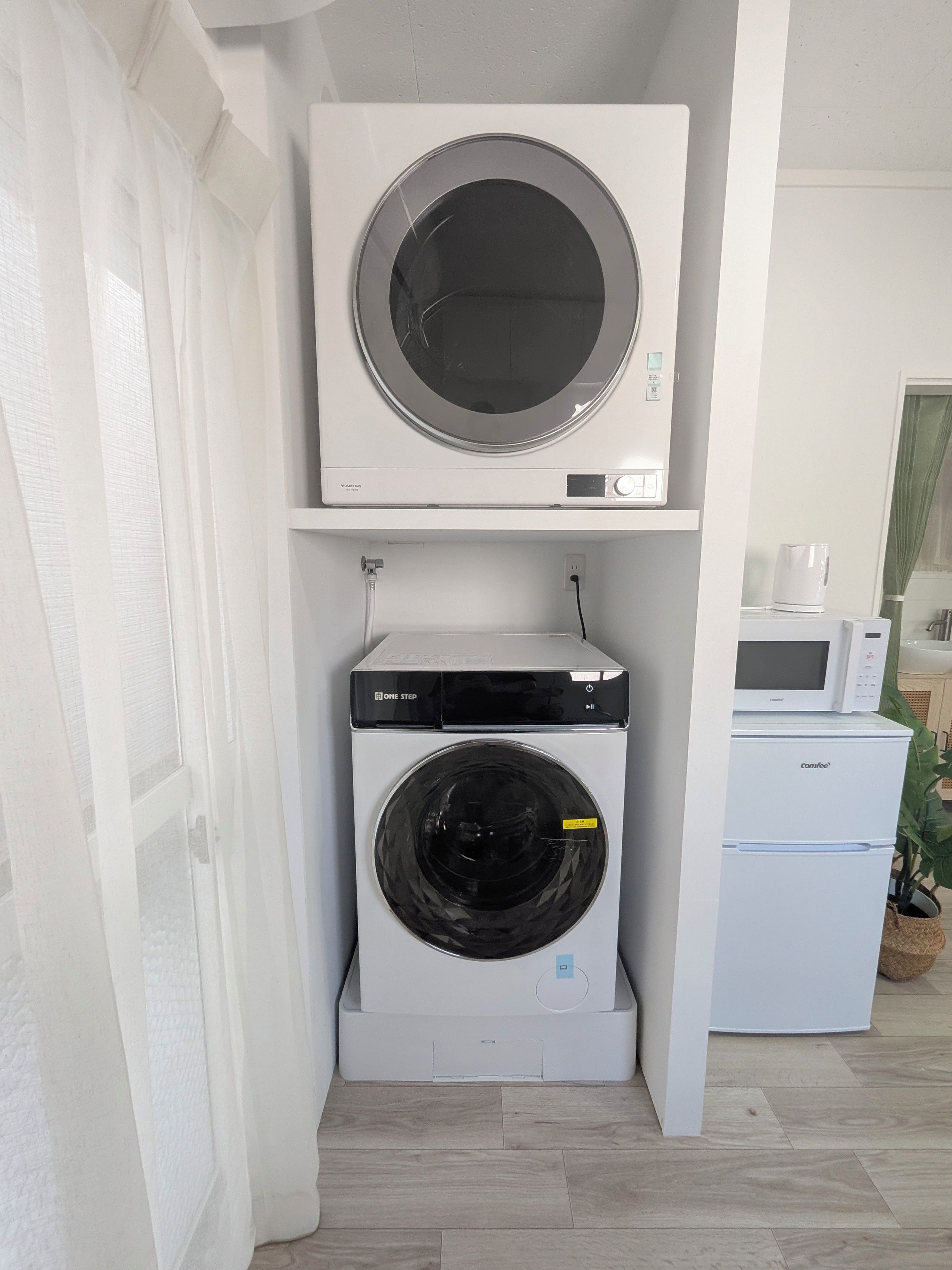 Un lavadero compacto con lavadora y secadora frontales, un microondas y un refrigerador pequeño.