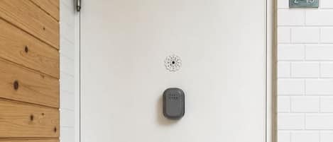 Una puerta blanca con cerradura electrónica, un felpudo y un buzón en la pared.