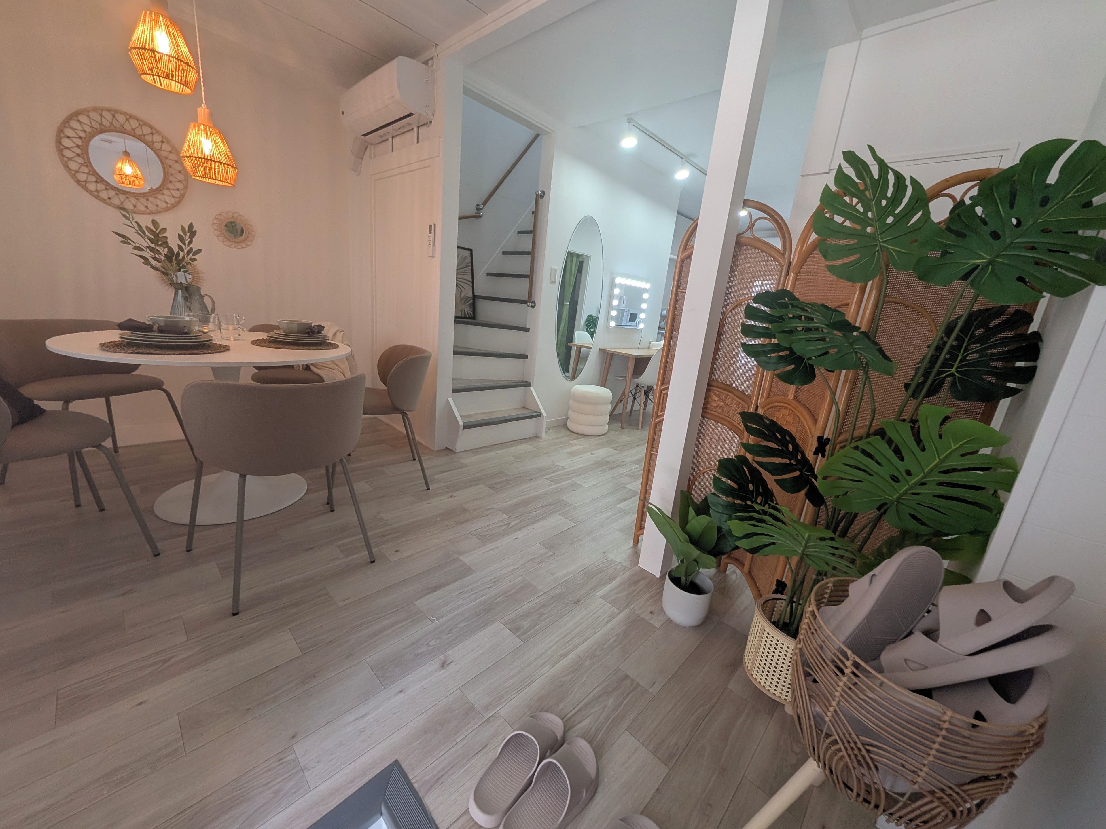 Een modern interieur met een eethoek, trap en een schoenenrek met planten.